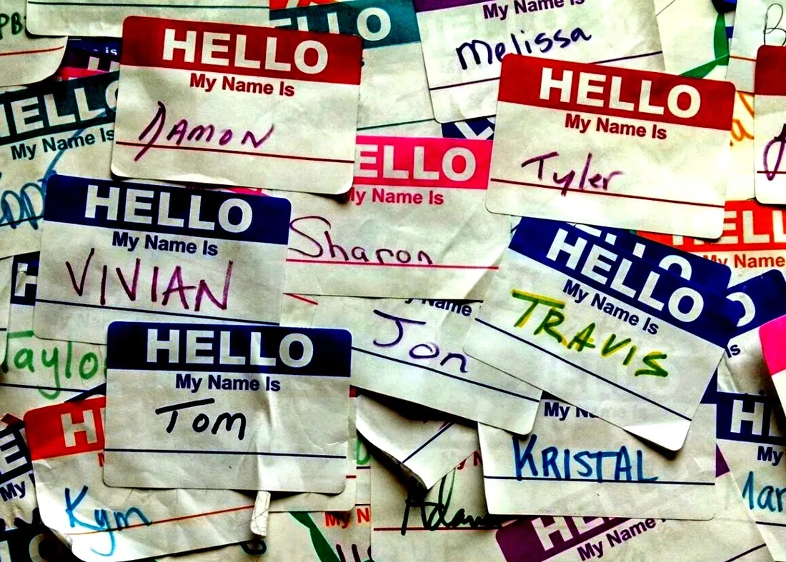 A heap of “Hello, my name is” stickers with first names handwritten in different colors.